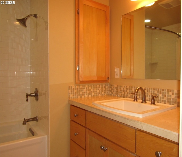 bathroom with vanity, decorative backsplash, and tiled shower / bath