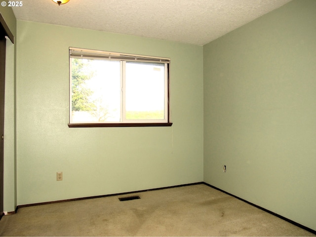 carpeted empty room with a textured ceiling