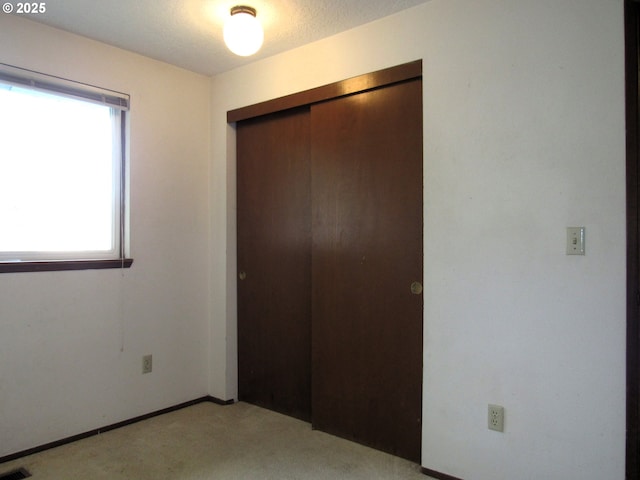 unfurnished bedroom with light colored carpet and a closet