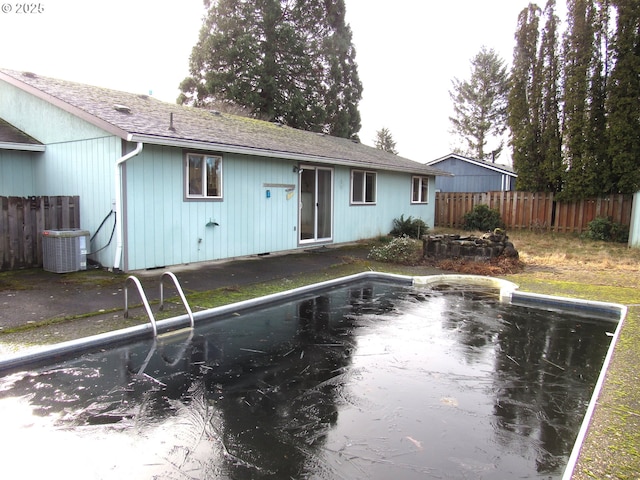 rear view of house with an empty pool and cooling unit