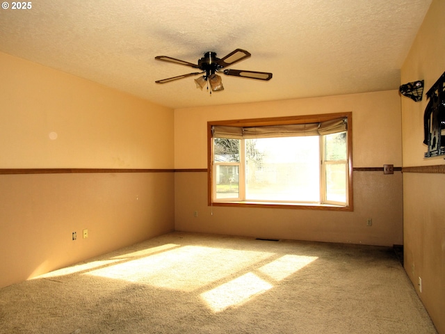 spare room featuring ceiling fan, carpet flooring, and a textured ceiling