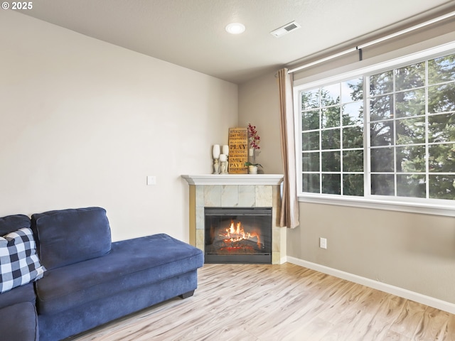 living area with a tiled fireplace and light wood-type flooring