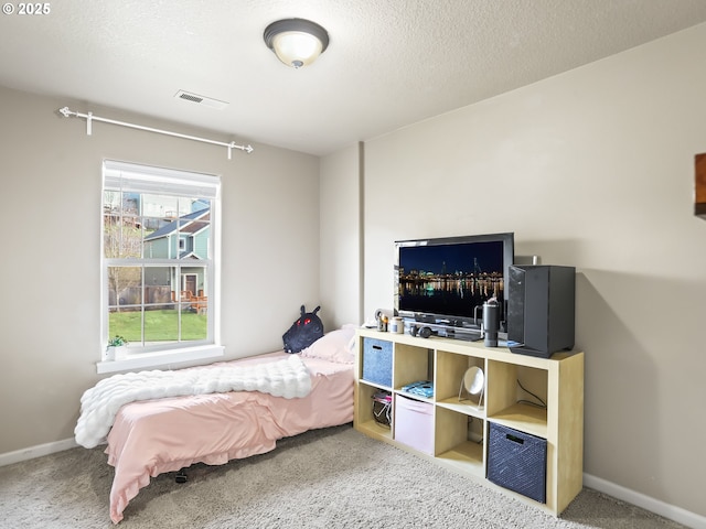 bedroom with a textured ceiling, carpet, visible vents, and baseboards