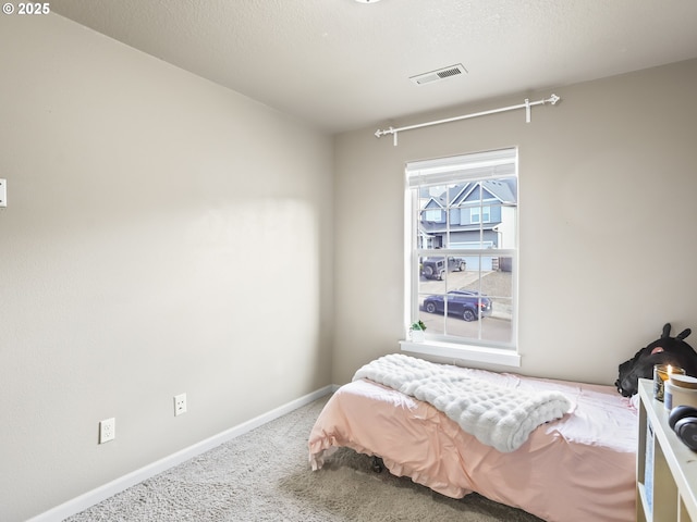 carpeted bedroom featuring visible vents, a textured ceiling, and baseboards