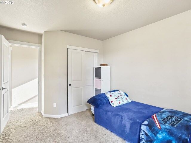 carpeted bedroom featuring a textured ceiling and a closet