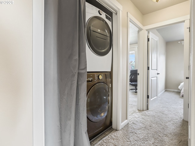 clothes washing area featuring stacked washer and clothes dryer and carpet