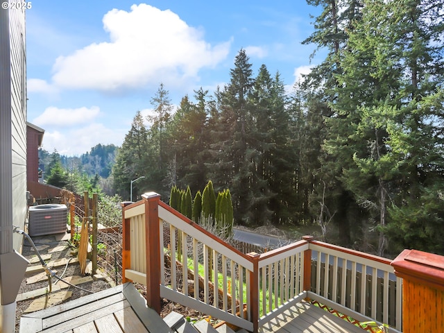 wooden deck featuring central AC and a view of trees