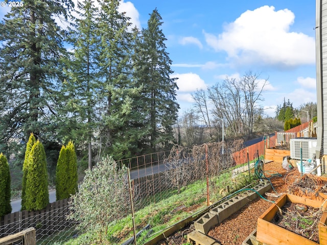 view of yard with a garden, fence, and central AC unit