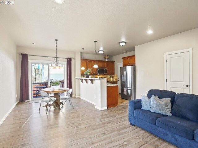 living room with an inviting chandelier, sink, and light wood-type flooring