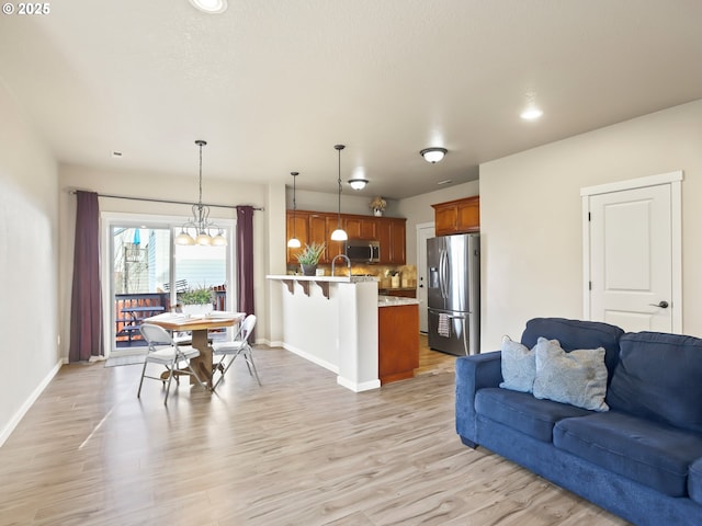 living room featuring light wood-style floors, a chandelier, and baseboards