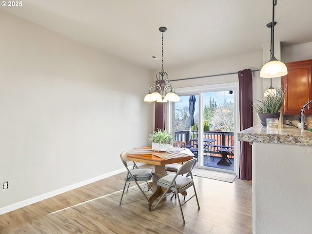 dining room with an inviting chandelier, sink, and light hardwood / wood-style flooring