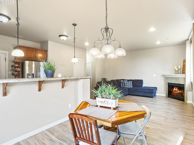 dining space with a tile fireplace and light wood-type flooring