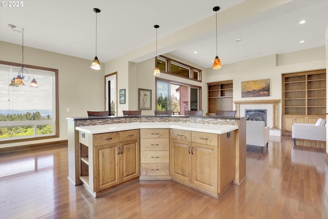 kitchen featuring light wood-type flooring, open shelves, built in features, and a glass covered fireplace