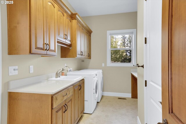 laundry room with visible vents, washer and dryer, baseboards, a sink, and cabinet space