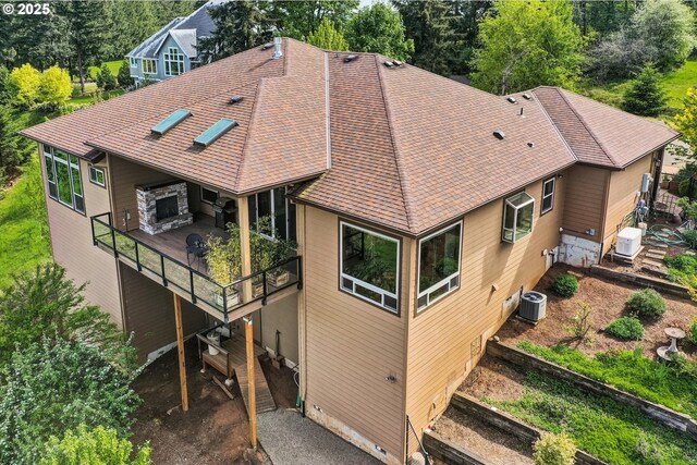 exterior space featuring a shingled roof, central AC, and a deck