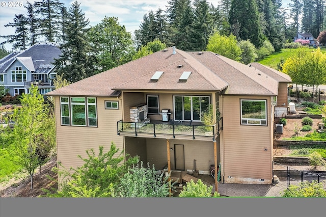 back of property featuring fence, a balcony, and roof with shingles