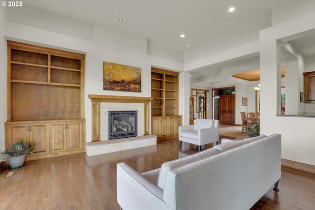 living room featuring built in features, recessed lighting, baseboards, wood finished floors, and a high end fireplace