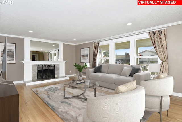 living room with a high end fireplace, a textured ceiling, and light wood-type flooring