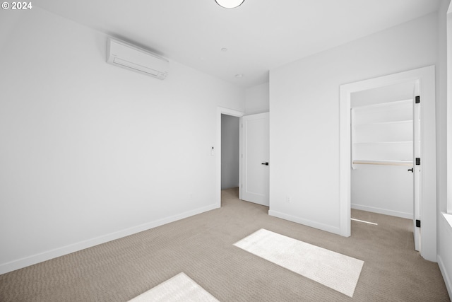 unfurnished bedroom featuring a wall unit AC, a spacious closet, a closet, and light colored carpet