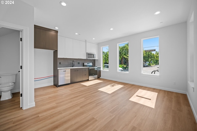 kitchen featuring sink, light hardwood / wood-style flooring, appliances with stainless steel finishes, white cabinetry, and dark brown cabinetry