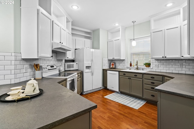 kitchen with white appliances, sink, light hardwood / wood-style flooring, decorative backsplash, and decorative light fixtures