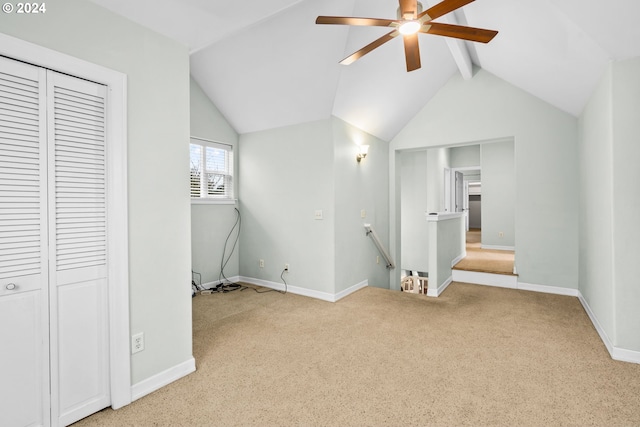 unfurnished bedroom featuring light carpet, vaulted ceiling with beams, a closet, and ceiling fan