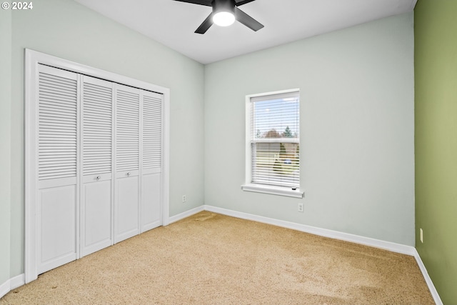 unfurnished bedroom with a closet, light colored carpet, and ceiling fan