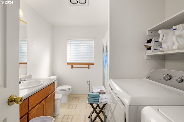 bathroom with vanity, washing machine and dryer, and toilet