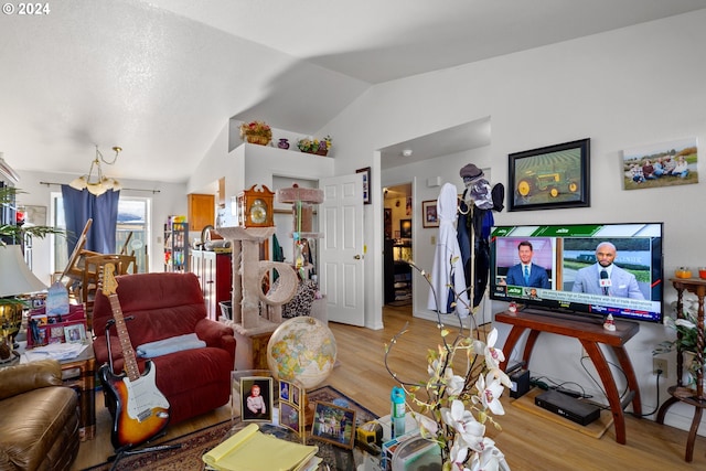 living room featuring lofted ceiling, wood-type flooring, and an inviting chandelier