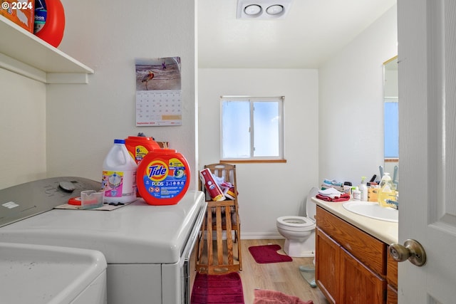 laundry room with sink, washer and dryer, and light wood-type flooring