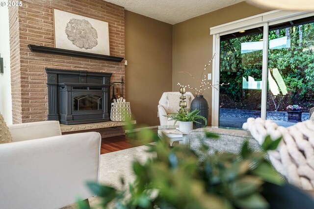 living room with wood finished floors, a textured ceiling, and a brick fireplace