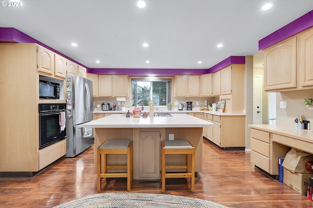 18095 Bluff Rd, Sandy, OR 97055 - kitchen featuring black appliances, a kitchen breakfast bar, a center island, light countertops, and dark wood-style flooring