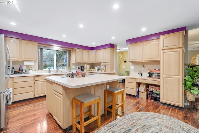 kitchen featuring a kitchen bar, stainless steel fridge, light brown cabinets, hardwood / wood-style floors, and a kitchen island