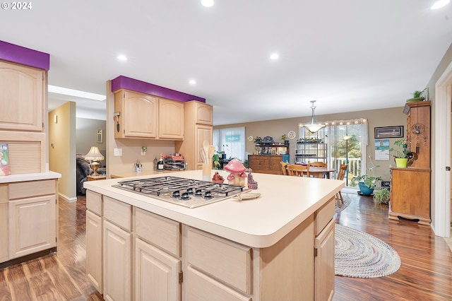 kitchen with a kitchen island, wood-type flooring, hanging light fixtures, and stainless steel gas cooktop