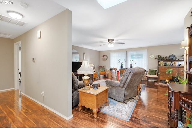 living room featuring ceiling fan, dark wood-type flooring, and a skylight