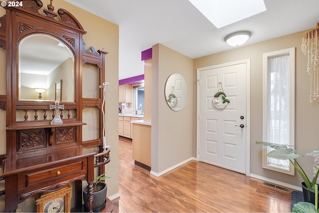 entrance foyer featuring a skylight and light wood-type flooring