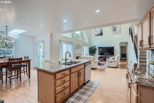 kitchen with stone counters, a kitchen island with sink, and sink