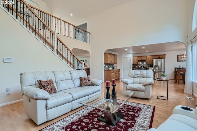 living room with a towering ceiling and light hardwood / wood-style flooring