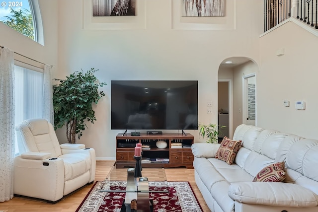 living room featuring light wood-type flooring and a towering ceiling