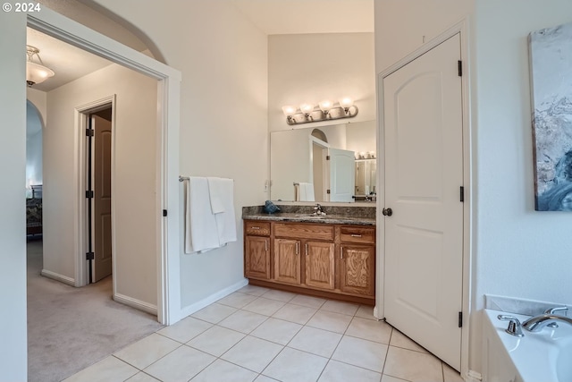 bathroom with tile patterned floors, a tub to relax in, and vanity