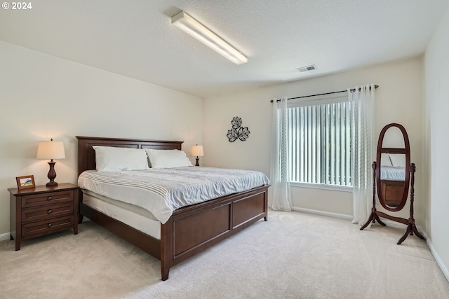 bedroom featuring light carpet and a textured ceiling