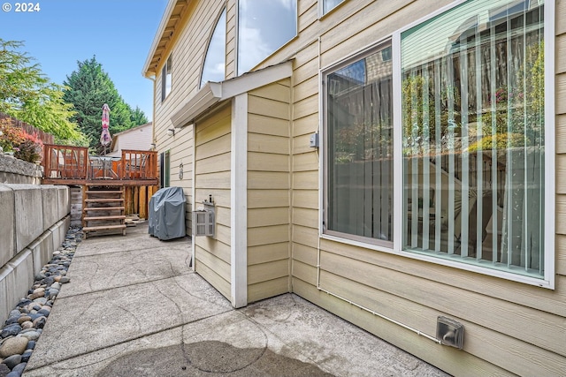 view of side of property featuring a wooden deck and a patio area