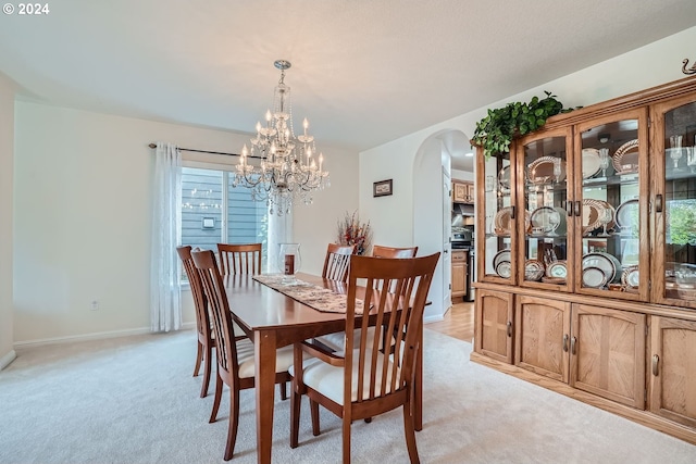 dining space featuring light colored carpet and a chandelier