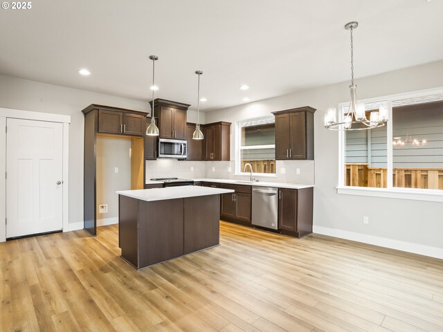 kitchen featuring stainless steel appliances, a center island, an inviting chandelier, backsplash, and hanging light fixtures