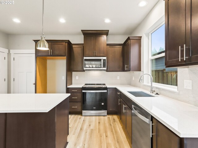 kitchen featuring light hardwood / wood-style flooring, decorative light fixtures, stainless steel appliances, backsplash, and sink