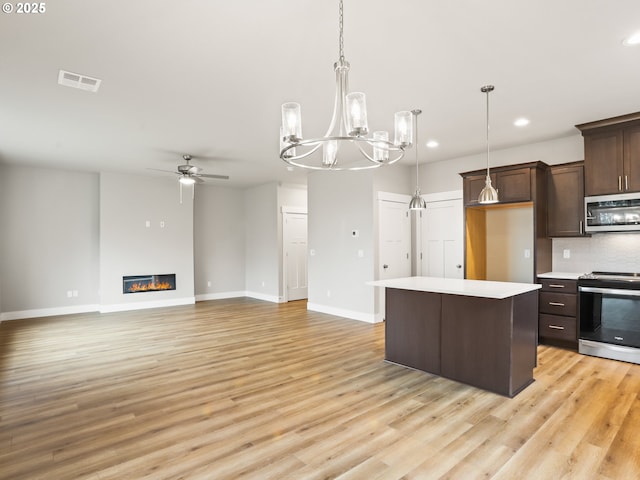 kitchen with hanging light fixtures, stainless steel appliances, backsplash, ceiling fan with notable chandelier, and dark brown cabinetry