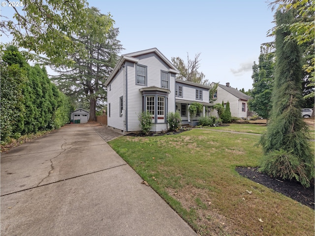 view of property featuring covered porch, a front yard, a garage, and an outdoor structure