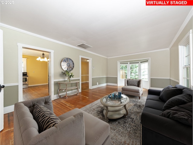 living room with a chandelier, hardwood / wood-style flooring, and crown molding