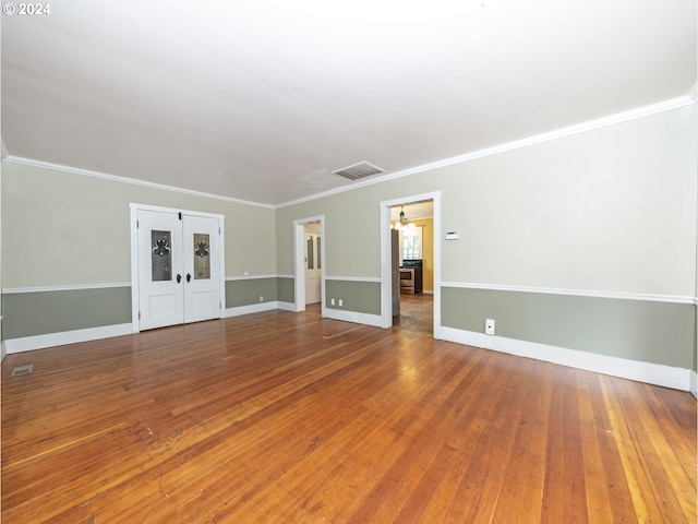 unfurnished living room featuring hardwood / wood-style flooring, french doors, and ornamental molding