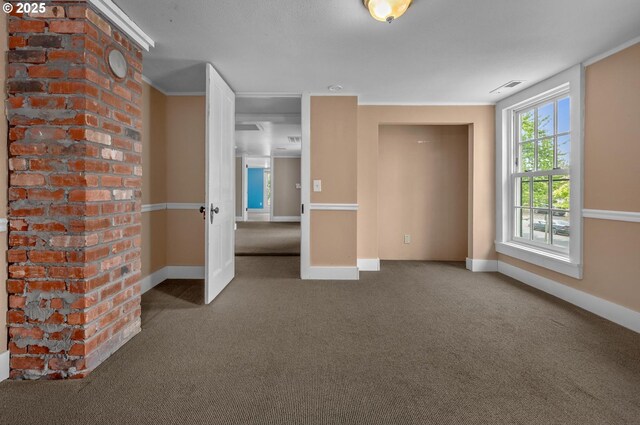 carpeted empty room featuring crown molding, baseboards, and visible vents
